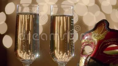 两杯香槟酒和狂欢节化妆面具。 背景上的Bokeh灯